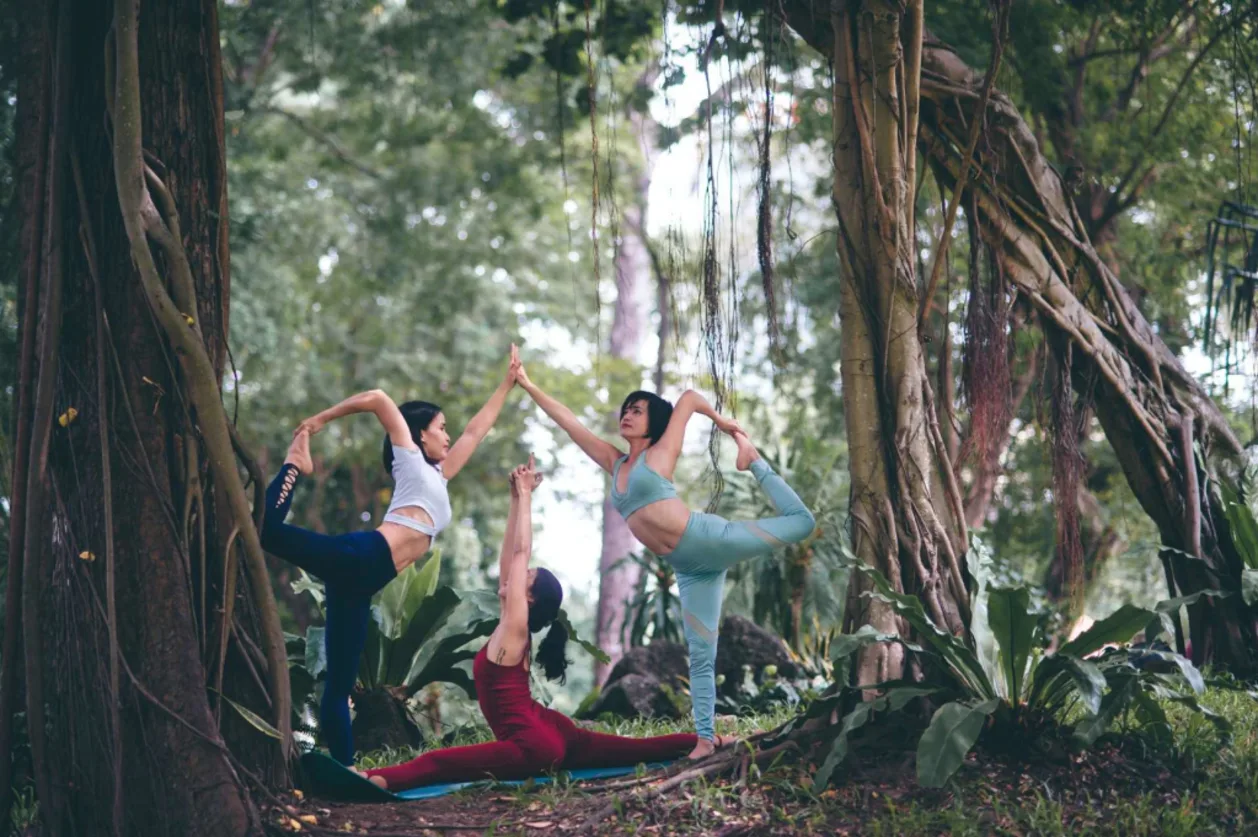 three women doing yoga poses in forest